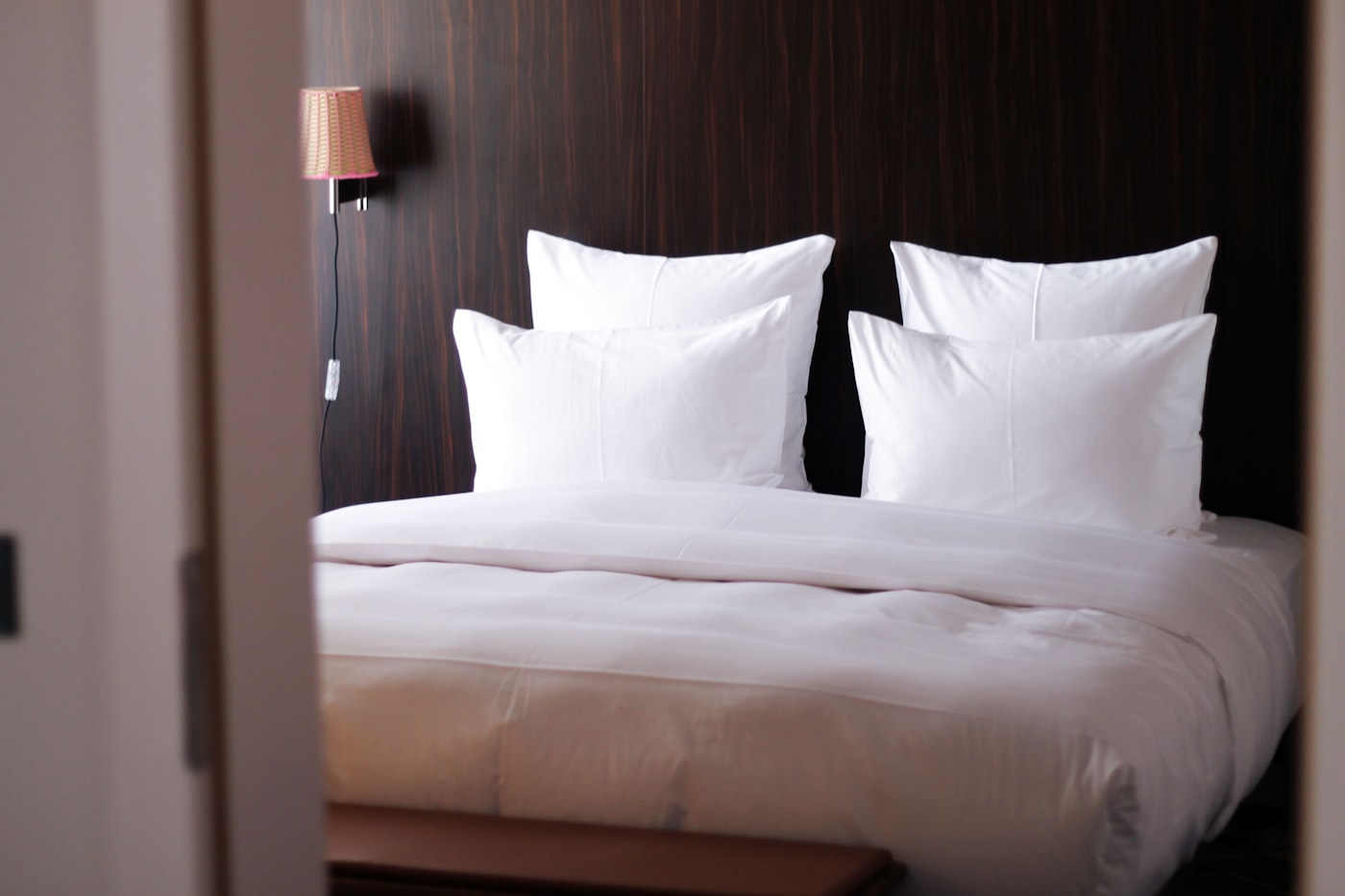 A made bed with white linen in morning light.