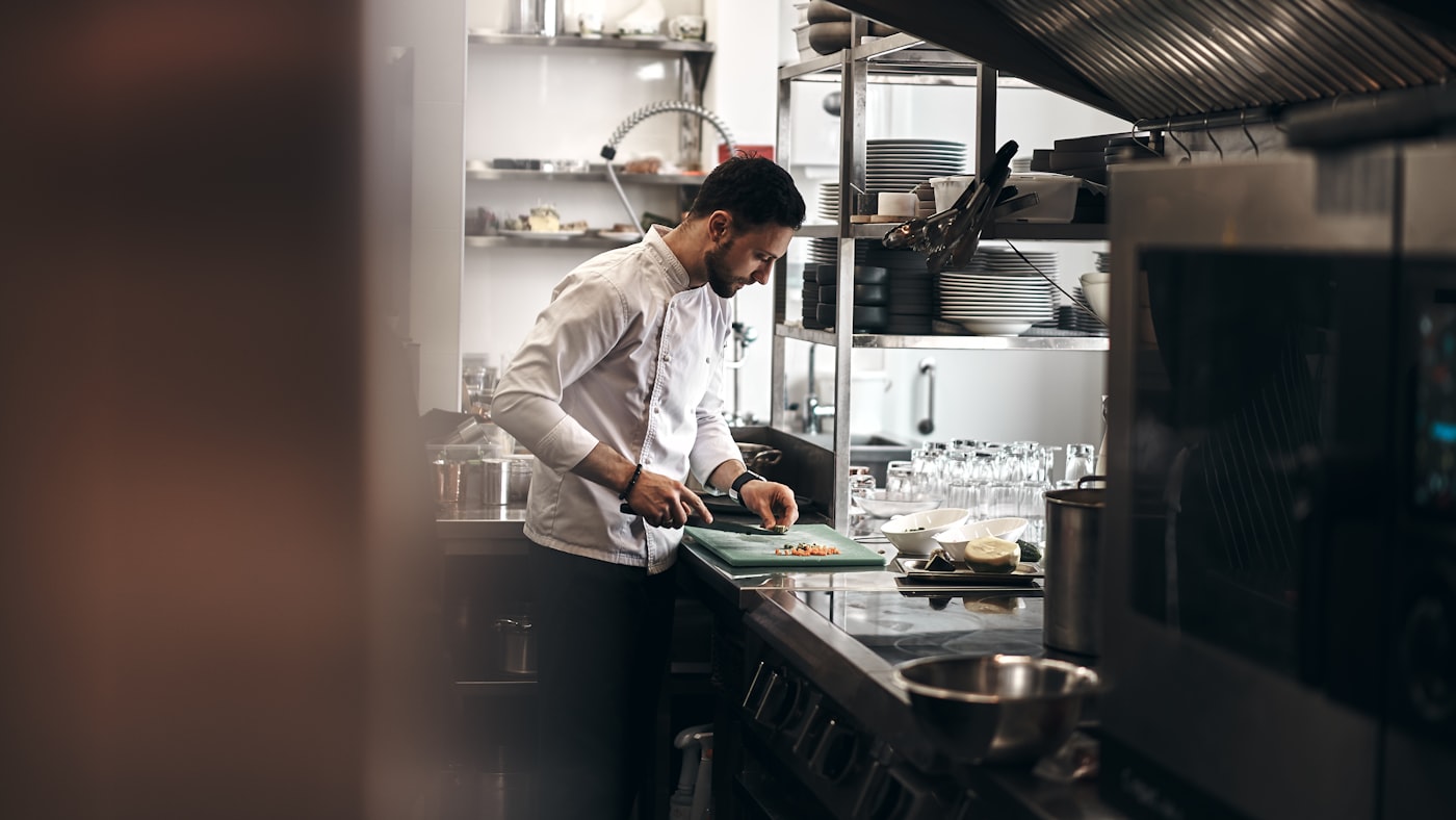 A chef working at the pass in a dark kitchen.
