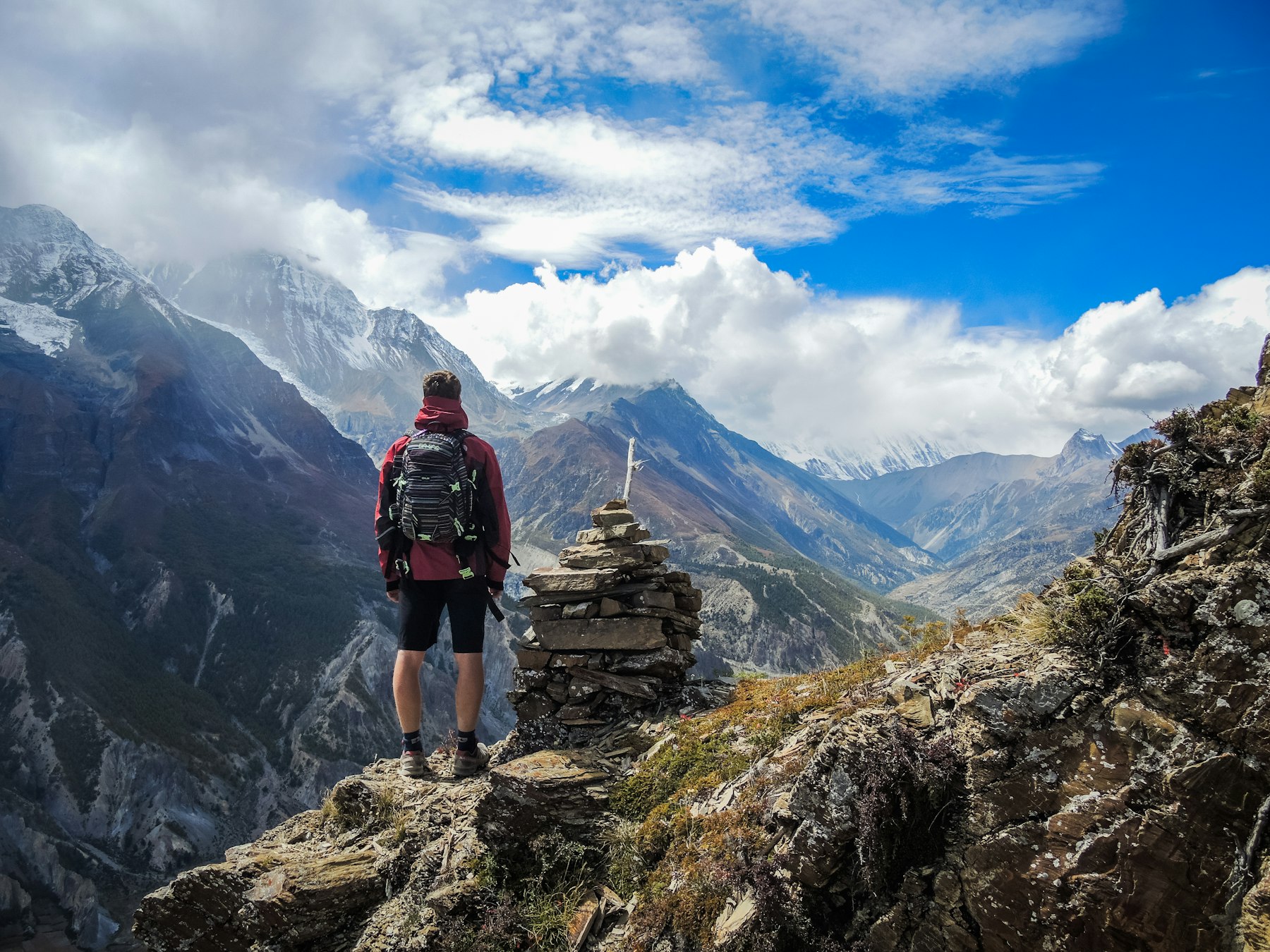 A walker standing beside a cairn on a ridge.